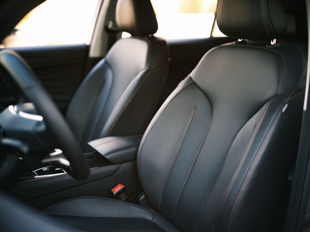 Der elektrisch verstellbare Fahrersitz mit schwarzem Kunstlederbezug und roten Ziernähten.