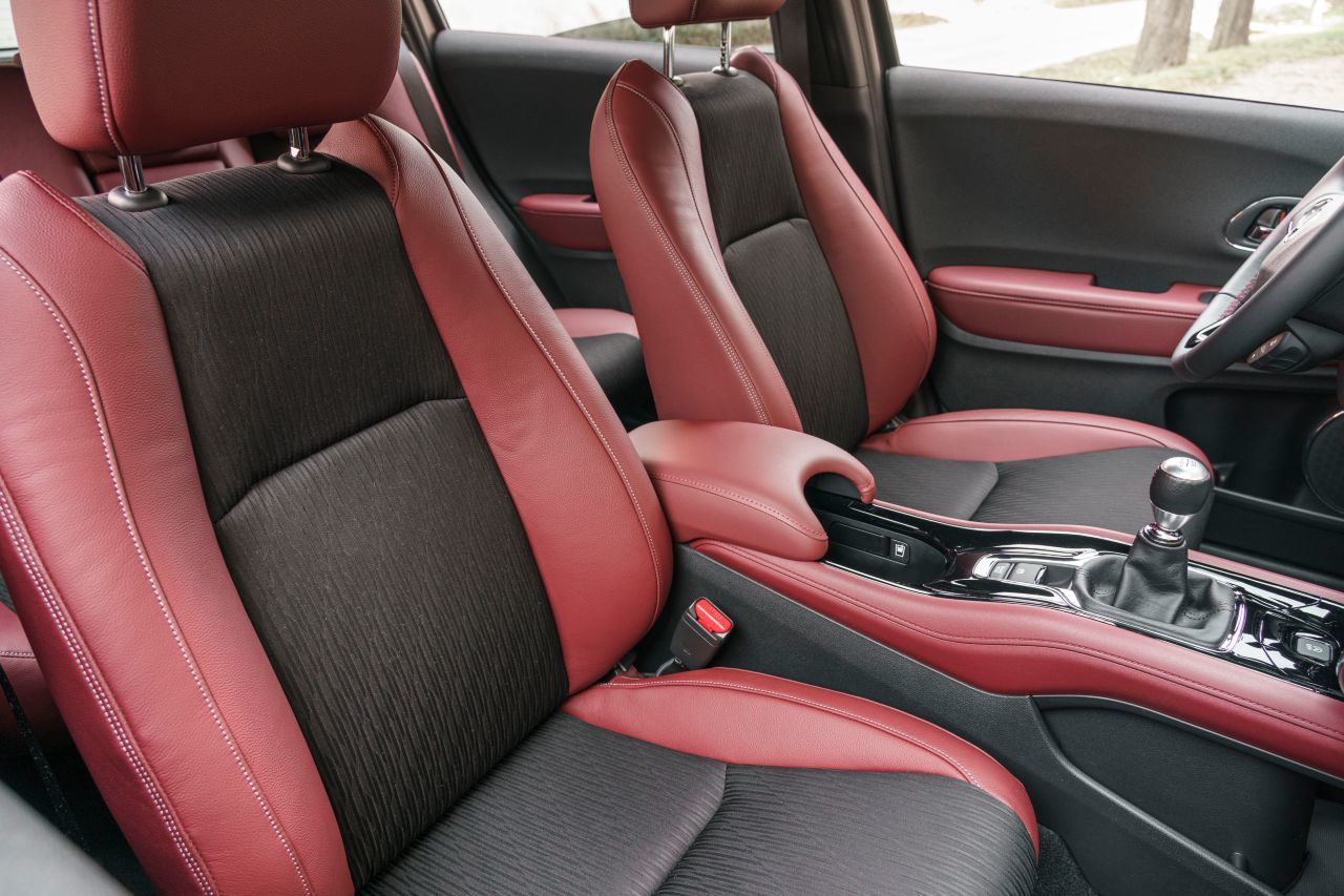 Die Sitze sind außen mit rotem Leder bezogen. Für Mittelkonsole und Armauflagen wird roter Kunststoff mit eingearbeiteten Ziernähten verwendet.